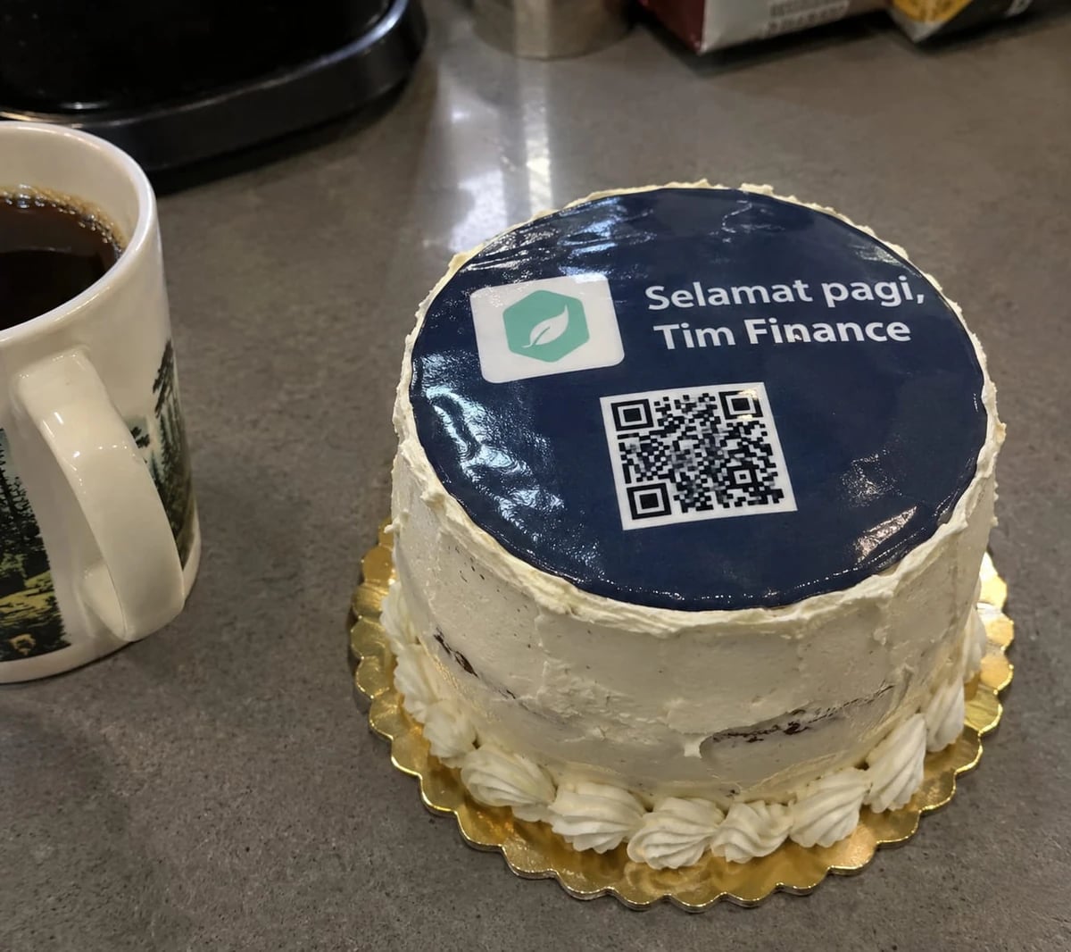 Cake reading “Selamat pagi, Tim Finance” next to a cup of coffee